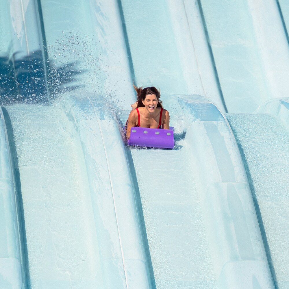 A mother and son race down the long waterslides of Toboggan Racers