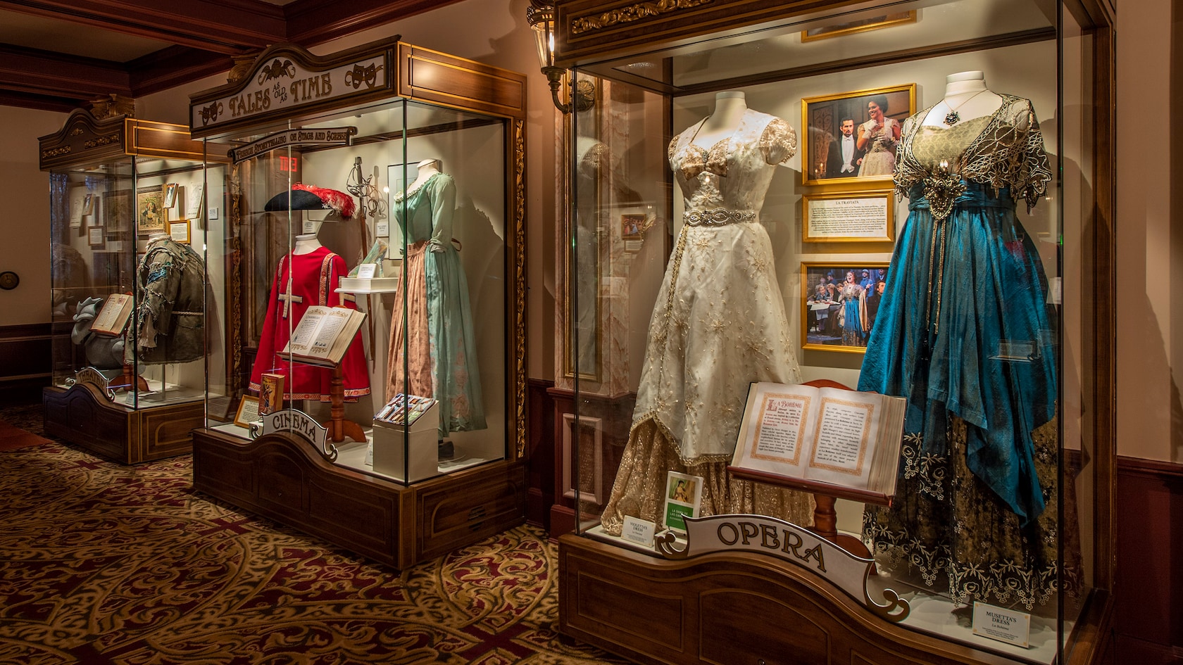Tres vitrinas iluminadas que contienen trajes, objetos de utilería y otros recuerdos de una variedad de presentaciones de teatro, cine y ópera.