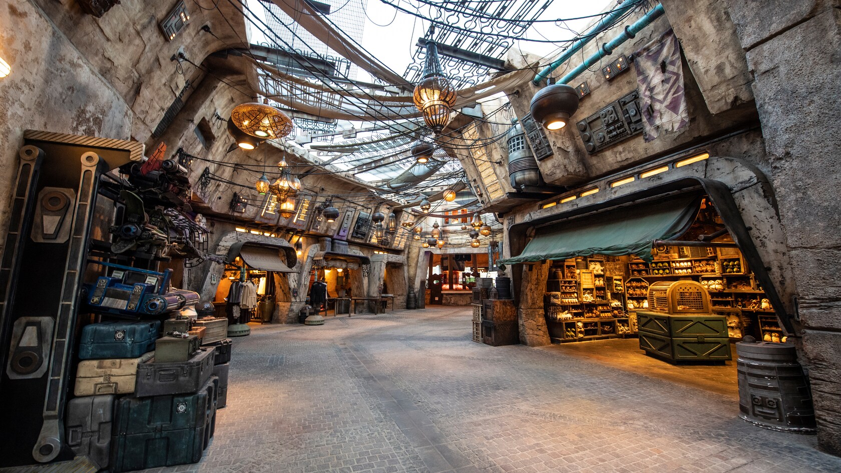 Long hallway between shops selling plush toys and clothing with many lanterns hanging from above