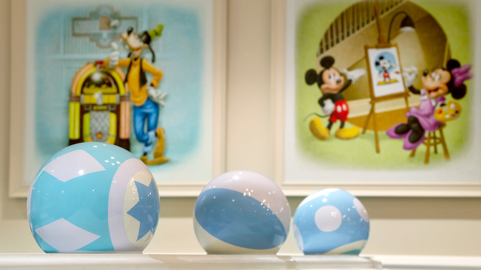 3 decorative balls in front of a painting of Goofy and a painting of Mickey Mouse and Minnie Mouse