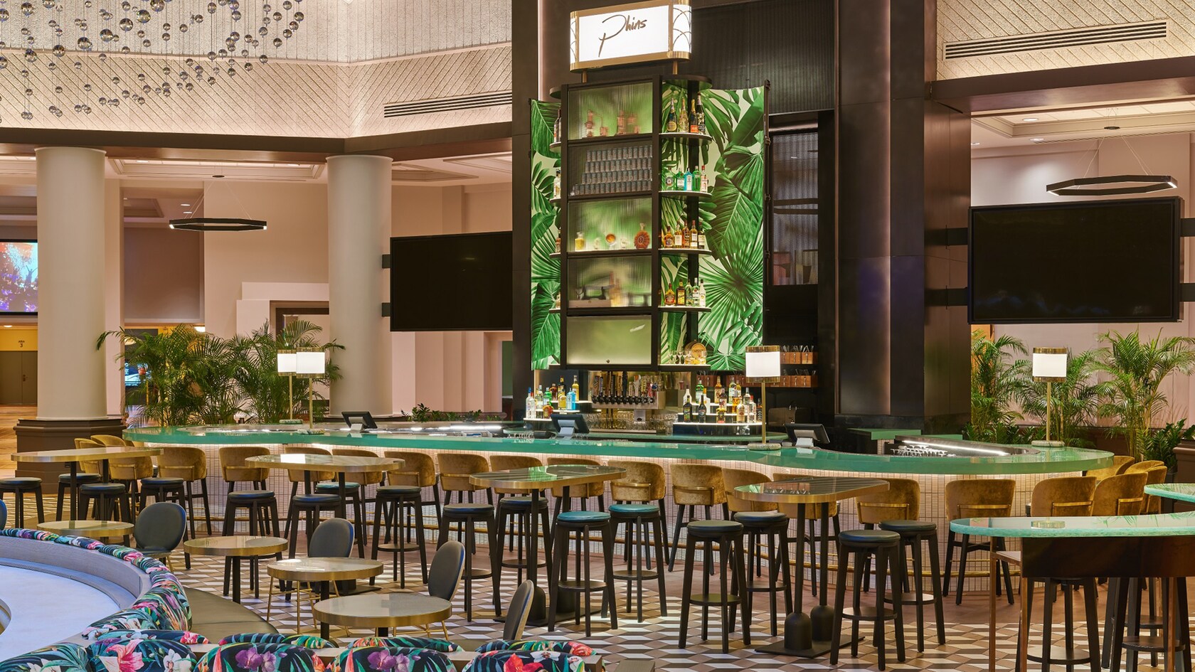 Phins lounge area, featuring a large curving bar surrounded by stools and several tables with stools nearby.