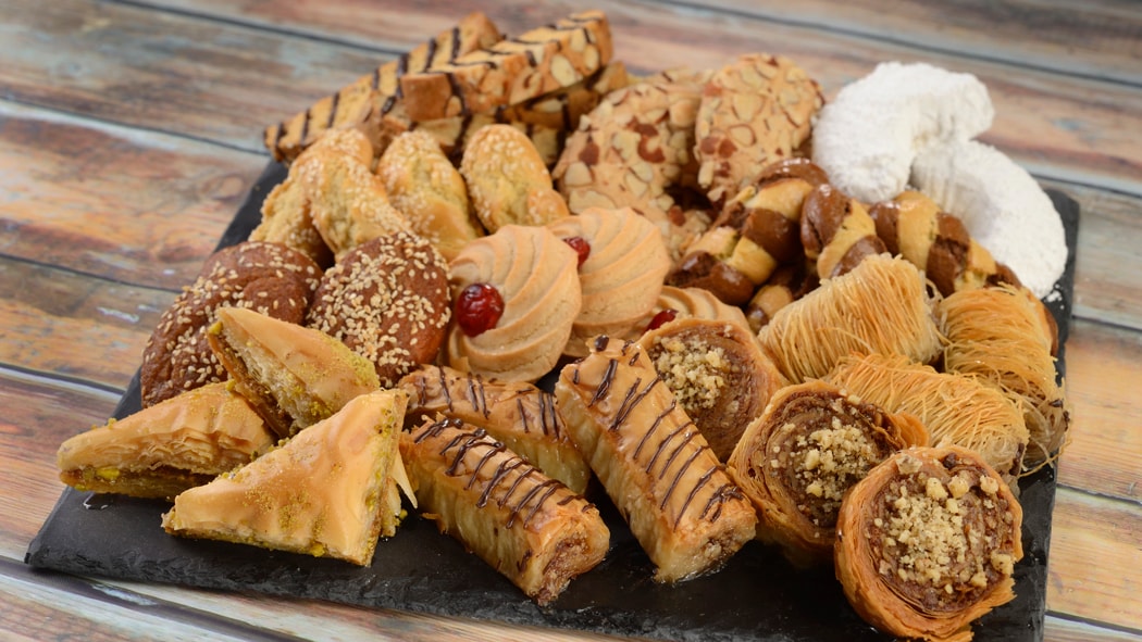 A selection of Moroccan themed pastries and cookies including pistachio baklava, almond crescent cookies and sesame koulouria.