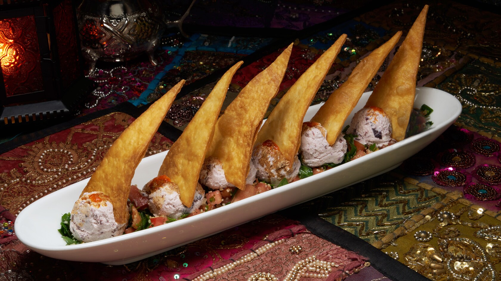 A long, narrow dish with 6 pointed, upright slices of bread all supported by scoops of goat cheese