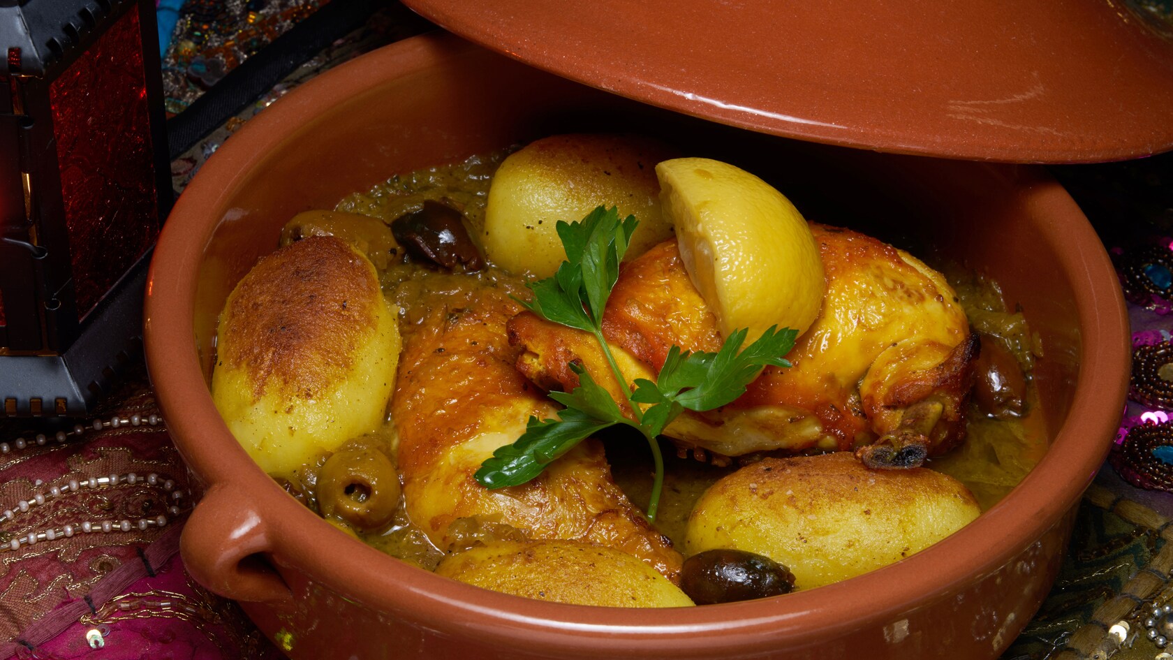 Half chickens served in a tagine with lemon wedges and olives