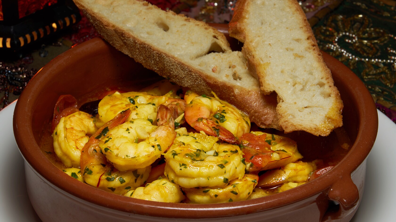 A tagine containing shrimp and a firm bread in a broth
