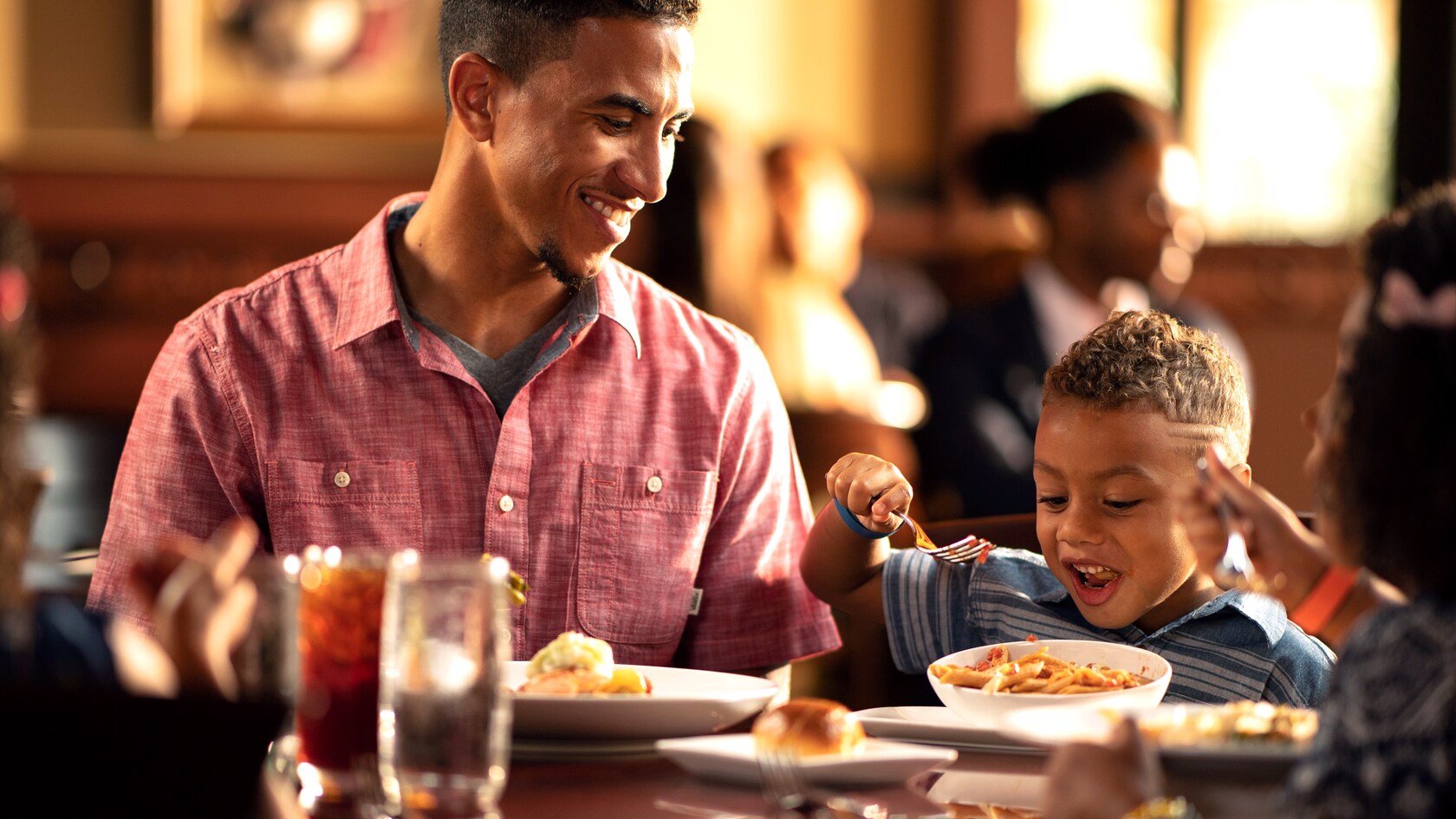 A father smiling at his young son while enjoying breakfast in a restaurant