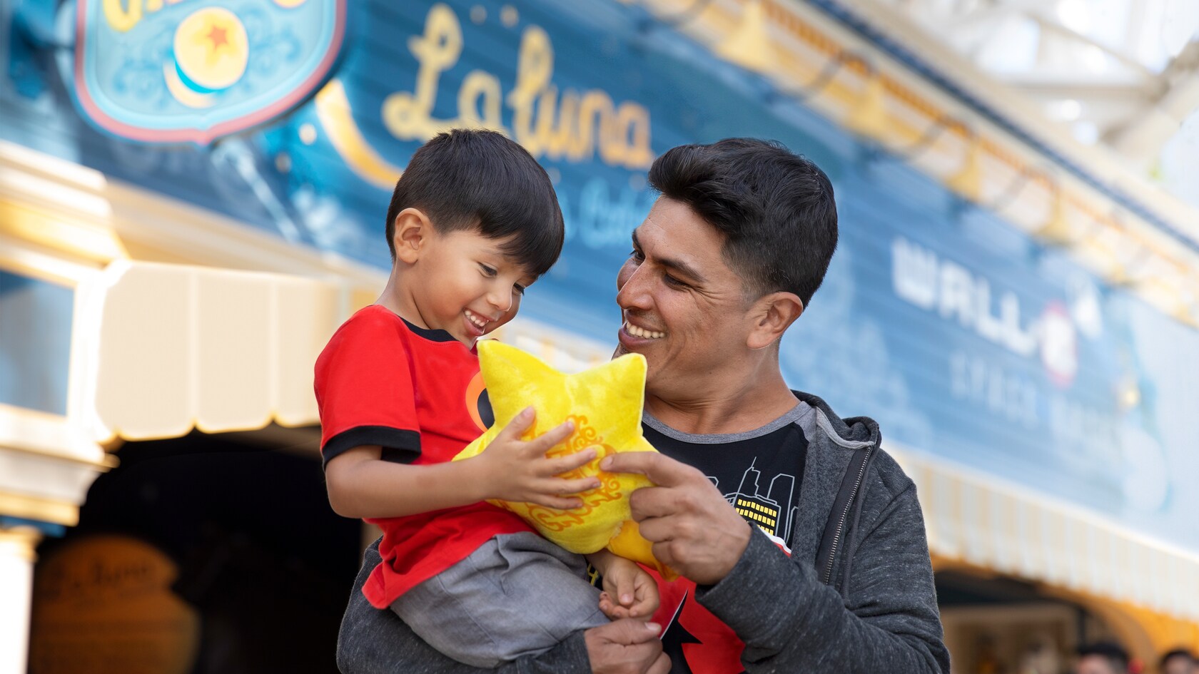A father gives his beaming son a plush pillow shaped like a star in front of La luna Star Catcher 