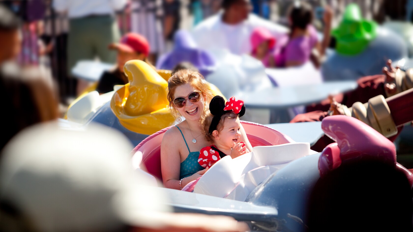 Una mujer alegre se prepara para subir a la atracción Dumbo the Flying Elephant con su hija sentada en sus piernas