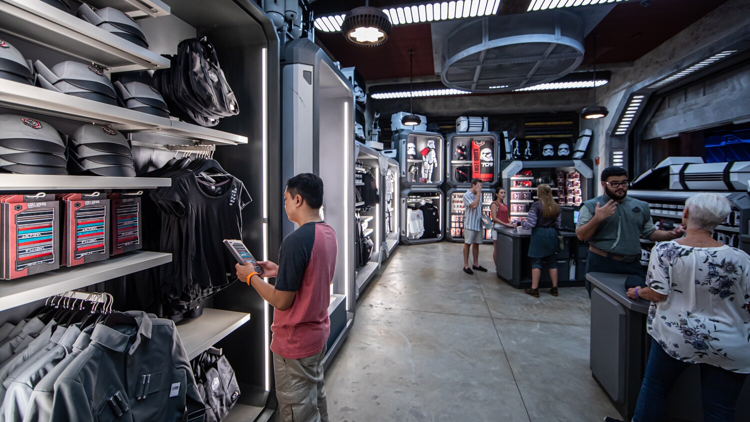 Inside First Order Cargo, Guests shop for supplies amid racks of apparel, hats and more.