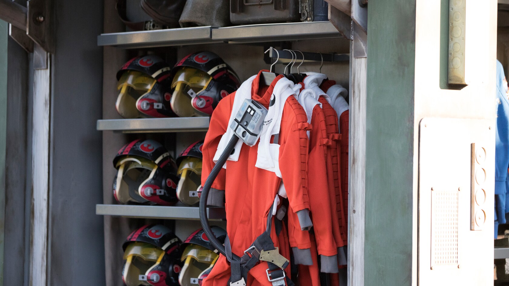 Shelves with Resistance pilot helmets and racks with Resistance pilot uniforms.