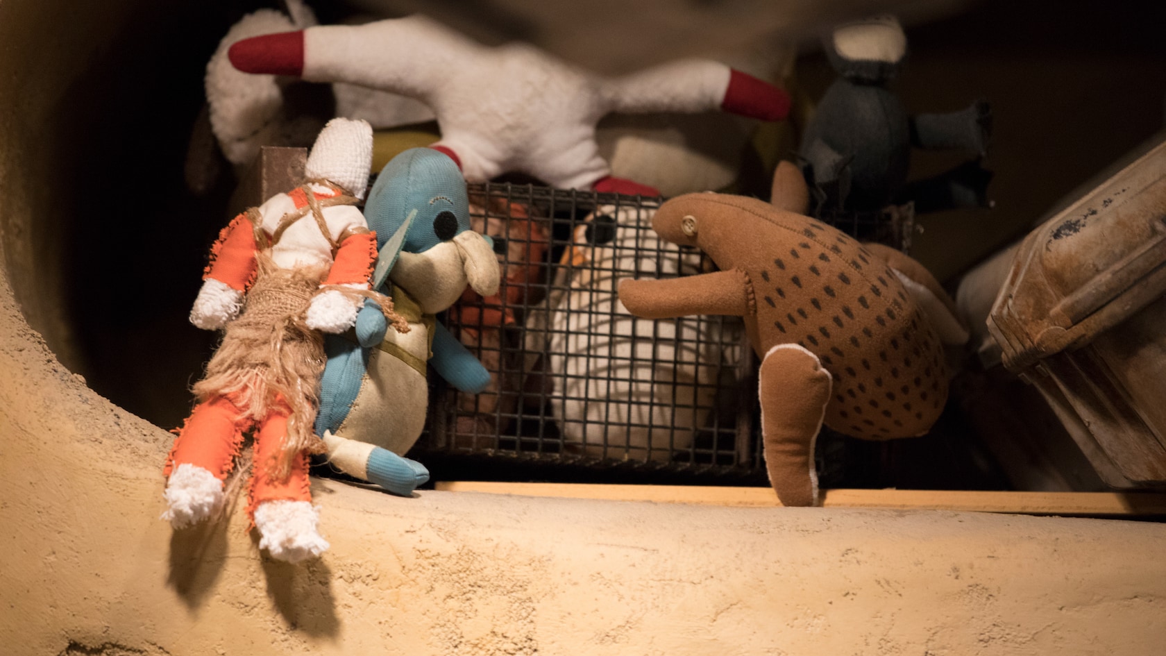 A plush porg in a container on a shelf besides a plush Watto, Rebel pilot and more.