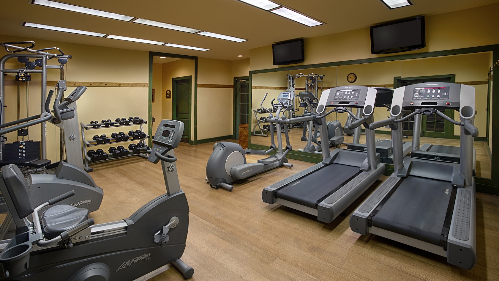 A fitness center with an exercise bike, treadmills, elliptical machine and weight lifting equipment