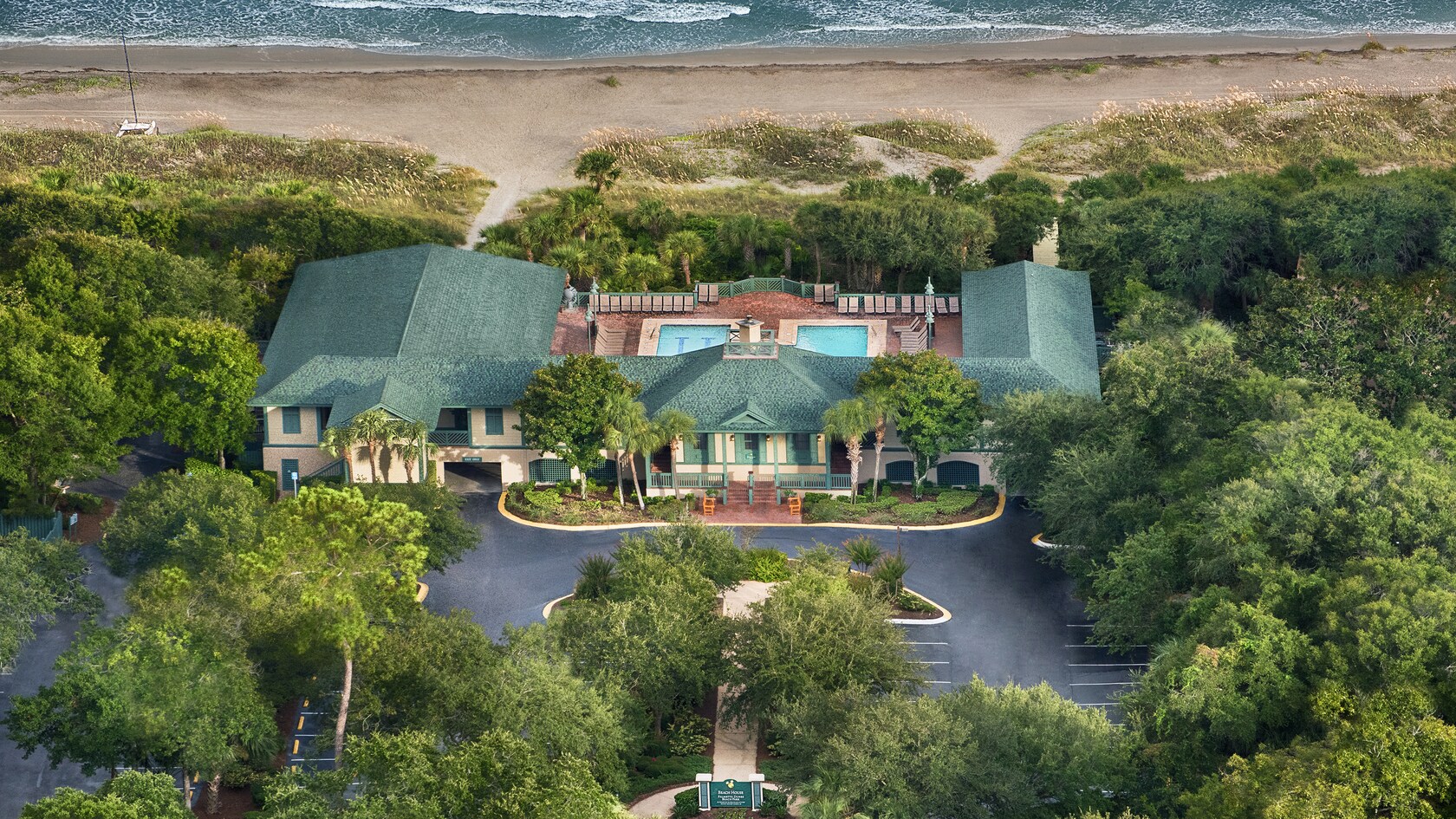 A rendering of a hotel building with 2 large pools in the back and surrounded by lush trees