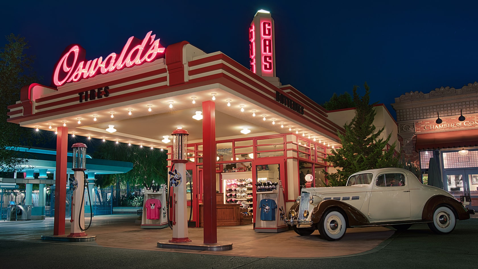 A shop that resembles a vintage gas station selling Oswald the Lucky Rabbit apparel, toys and Mickey Mouse ear hats with a classic car parked out front and signs that read "Oswald's, Tires, Batteries and Gas"