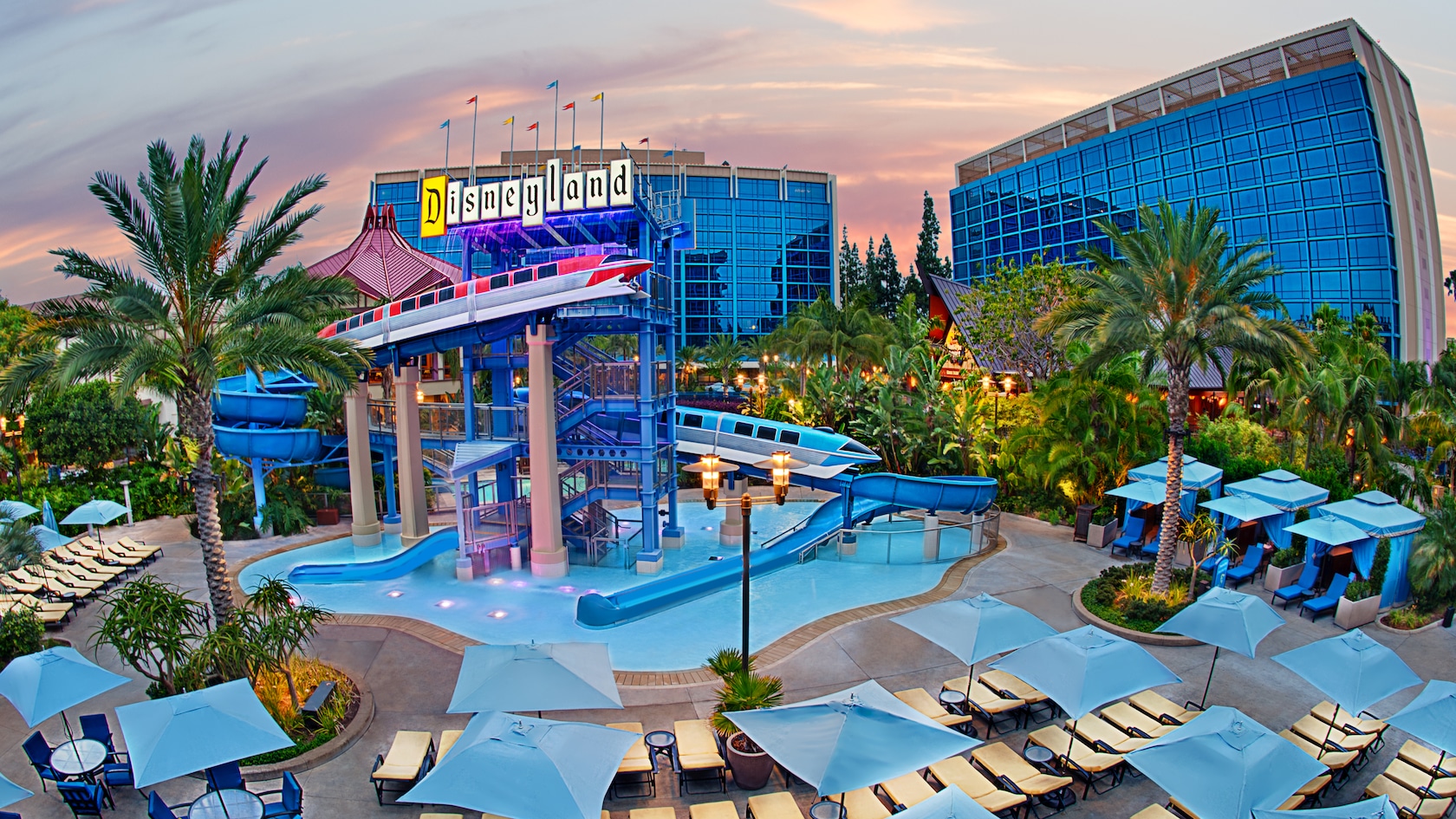 Sunshine brightens the pools, waterslide, poolside cabanas and lounge chairs among the palm trees