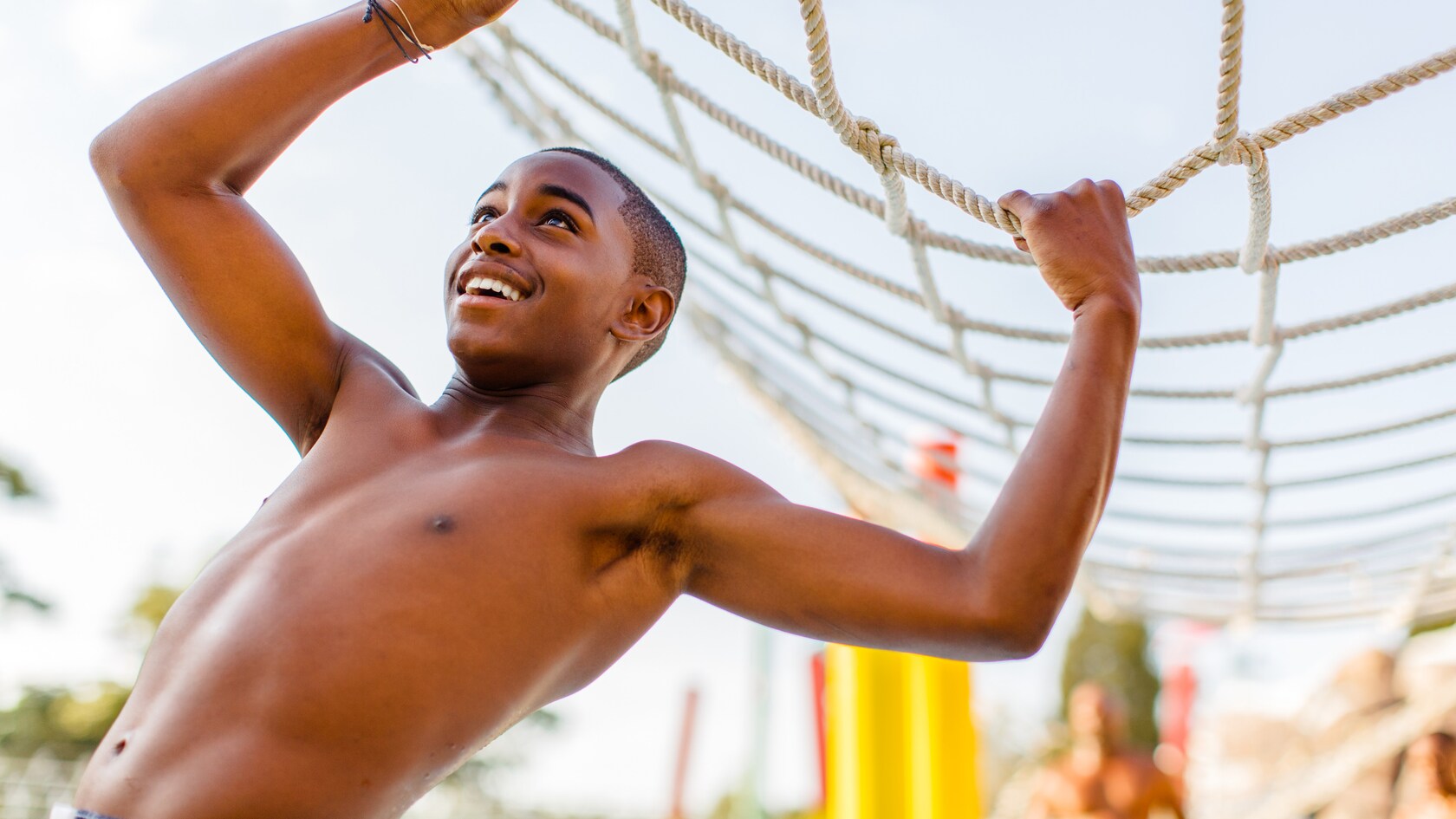 A teenaged boy grasps the cargo net at Thin Ice Training Course in Ski Patrol Training Camp
