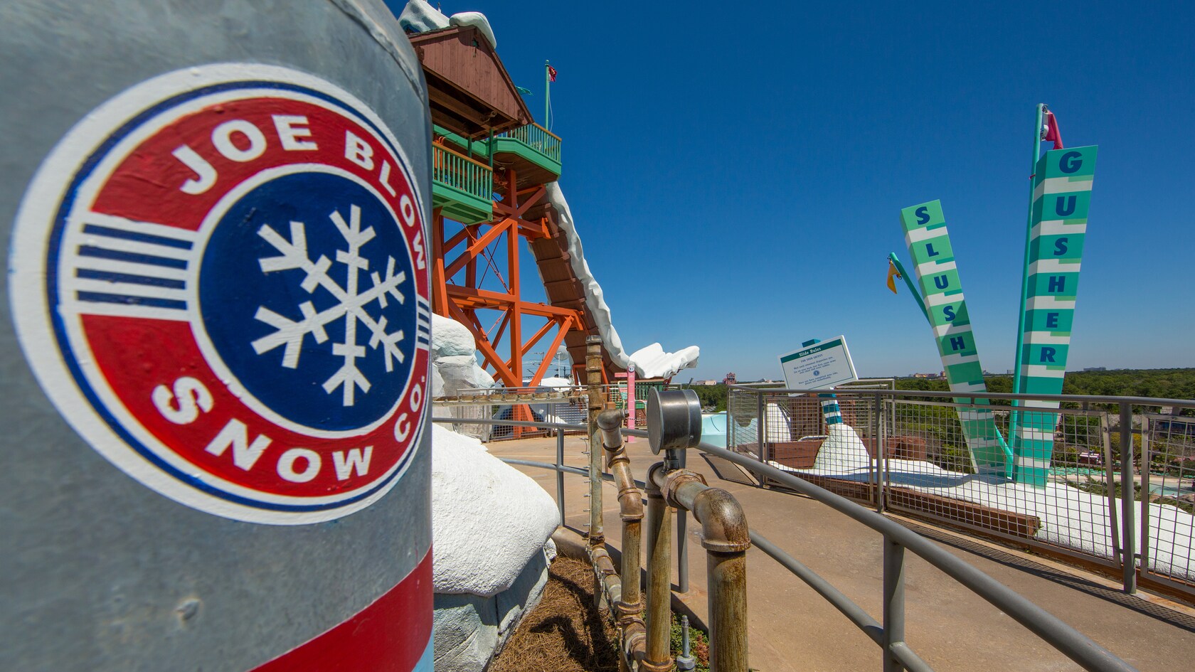 Near the start of Slush Gusher with a structure labeled Joe Blow Snow Co. and the ride's sign