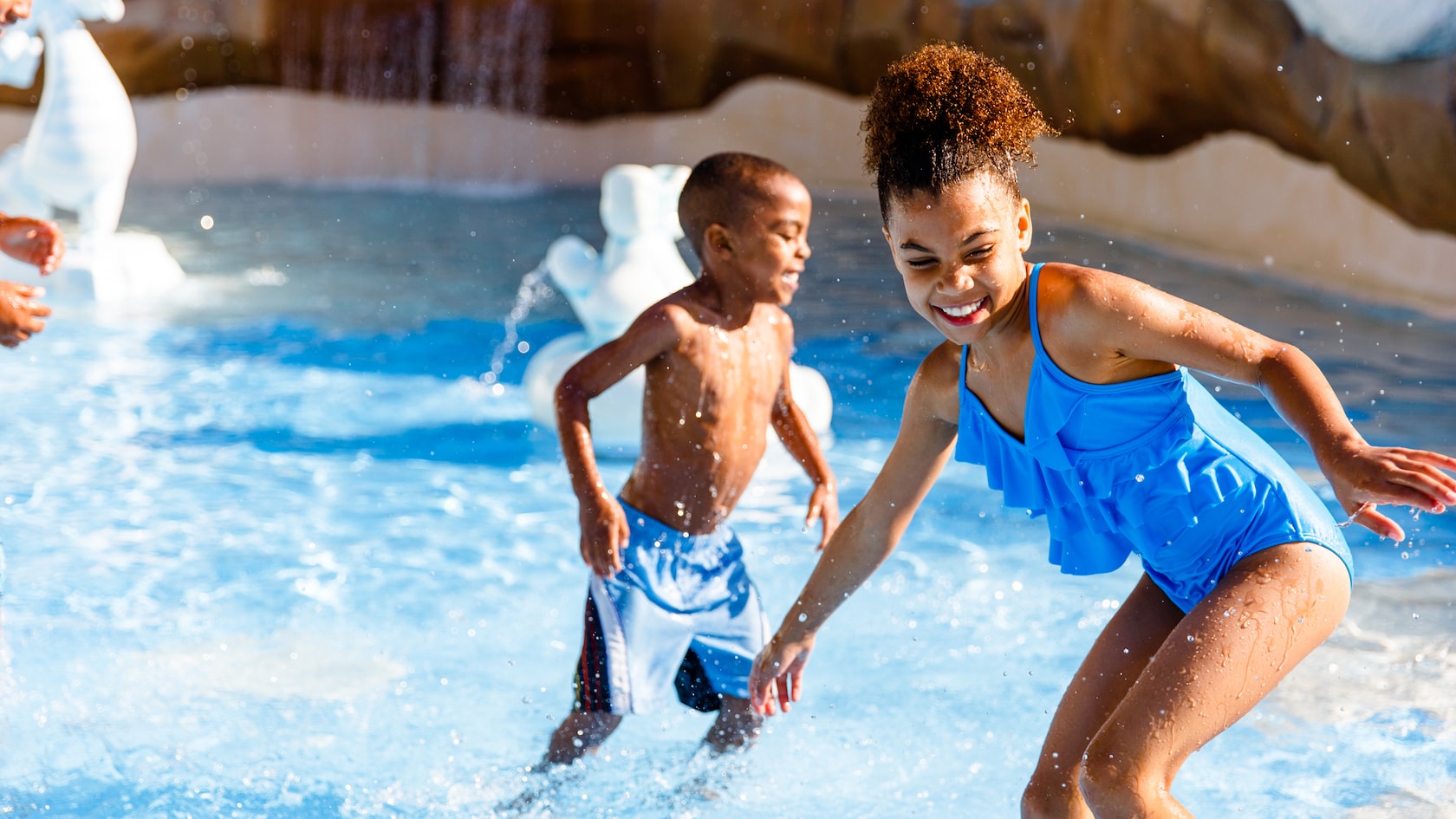 A young boy and his sister frolic in a wading pool