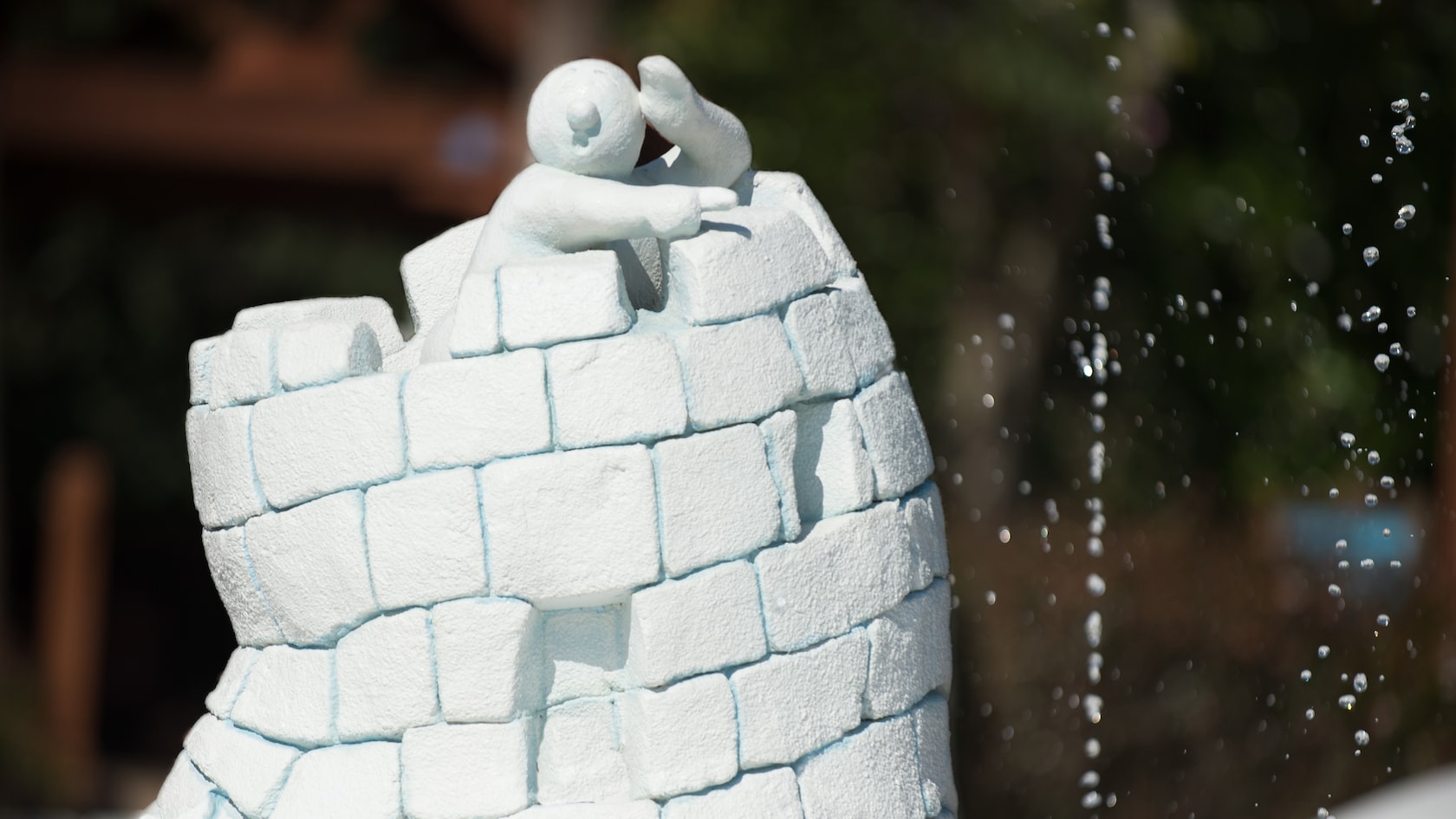 A small sculpture of a snowman pointing while standing in a ice-cube turret