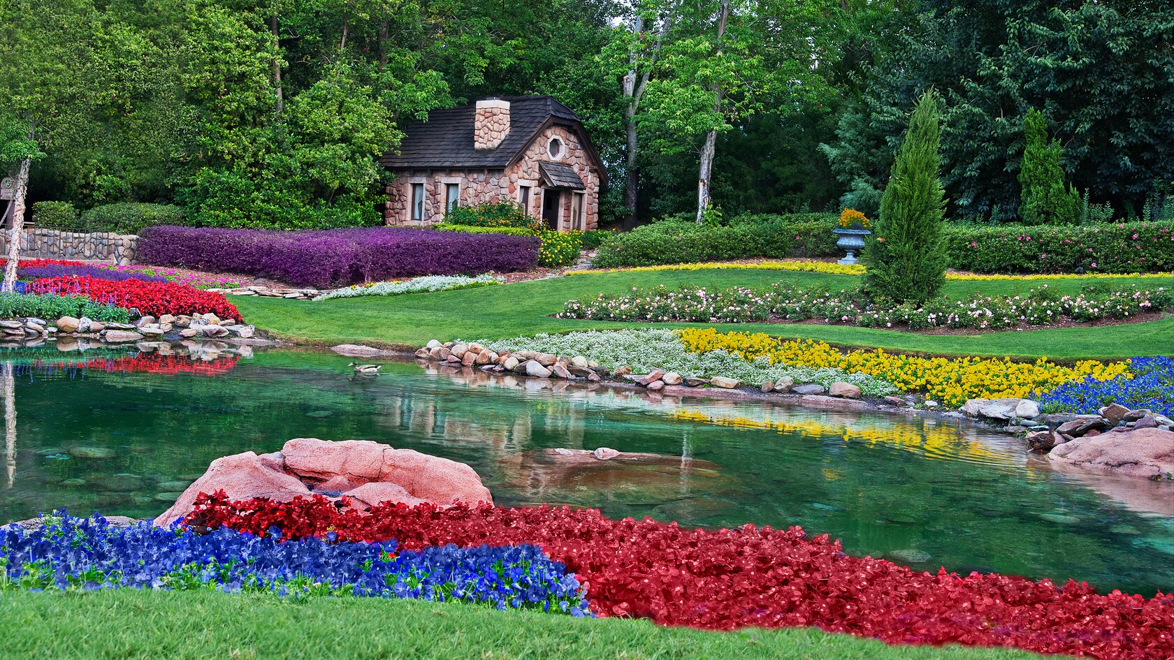 Los Victoria Gardens con coloridas flores, un estanque y una pequeña casa de piedra en el pabellón de Canadá
