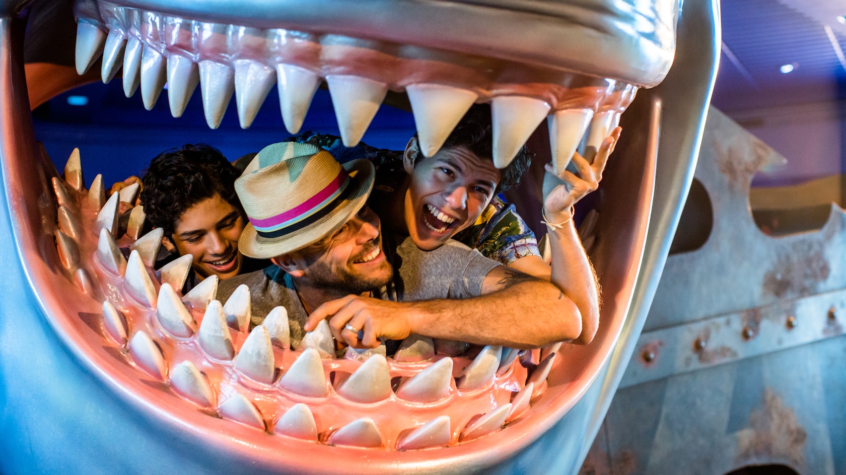 A dad and his 2 teenage sons play inside Bruce the shark's mouth with rows of teeth