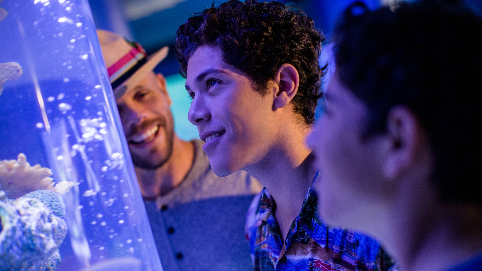 A dad watches his 2 teenage sons looking at a fish aquarium at SeaBase