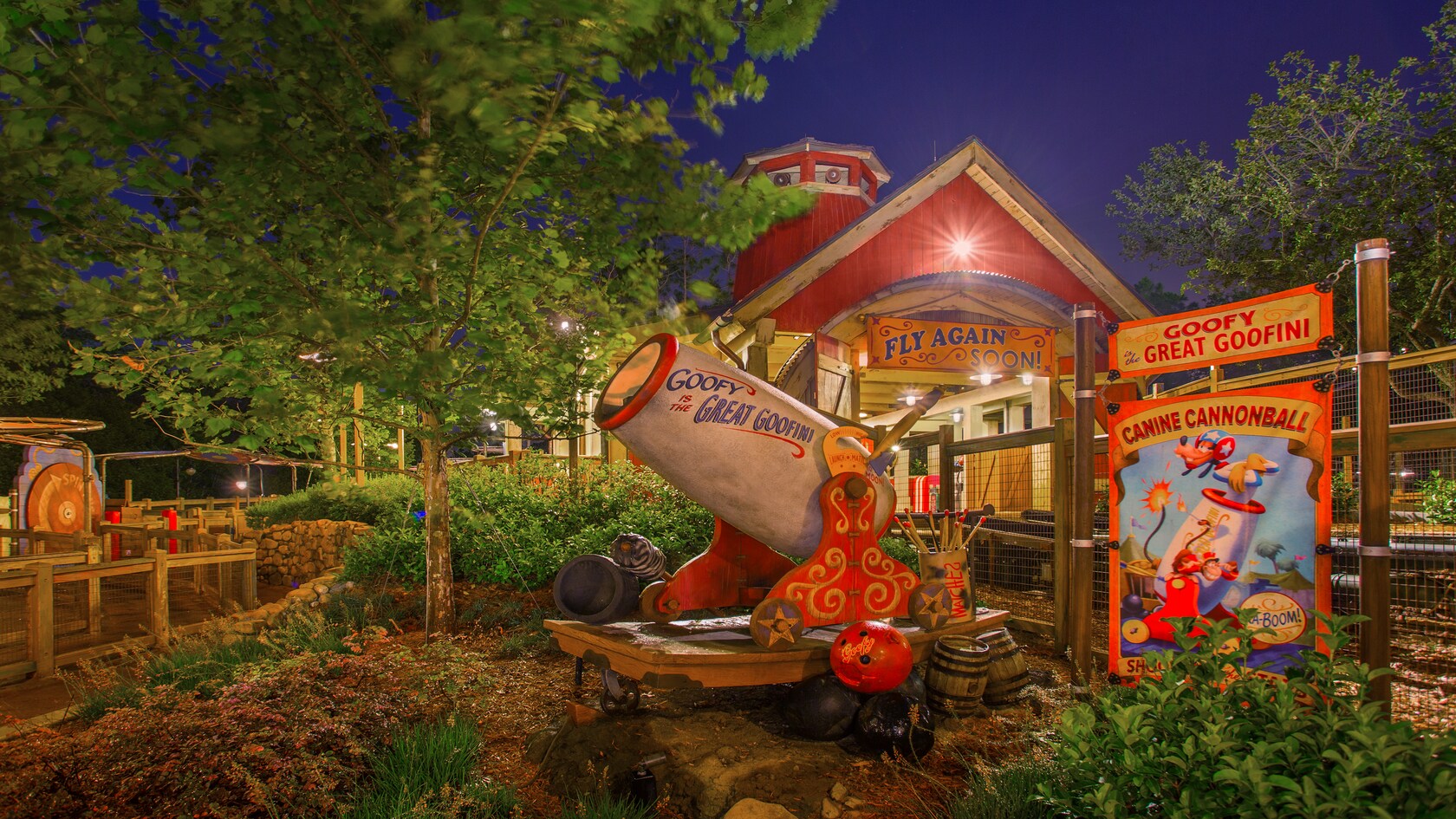 A cannon sits next to a sign featuring Goofy as the Canine Cannonball at The Barnstormer
