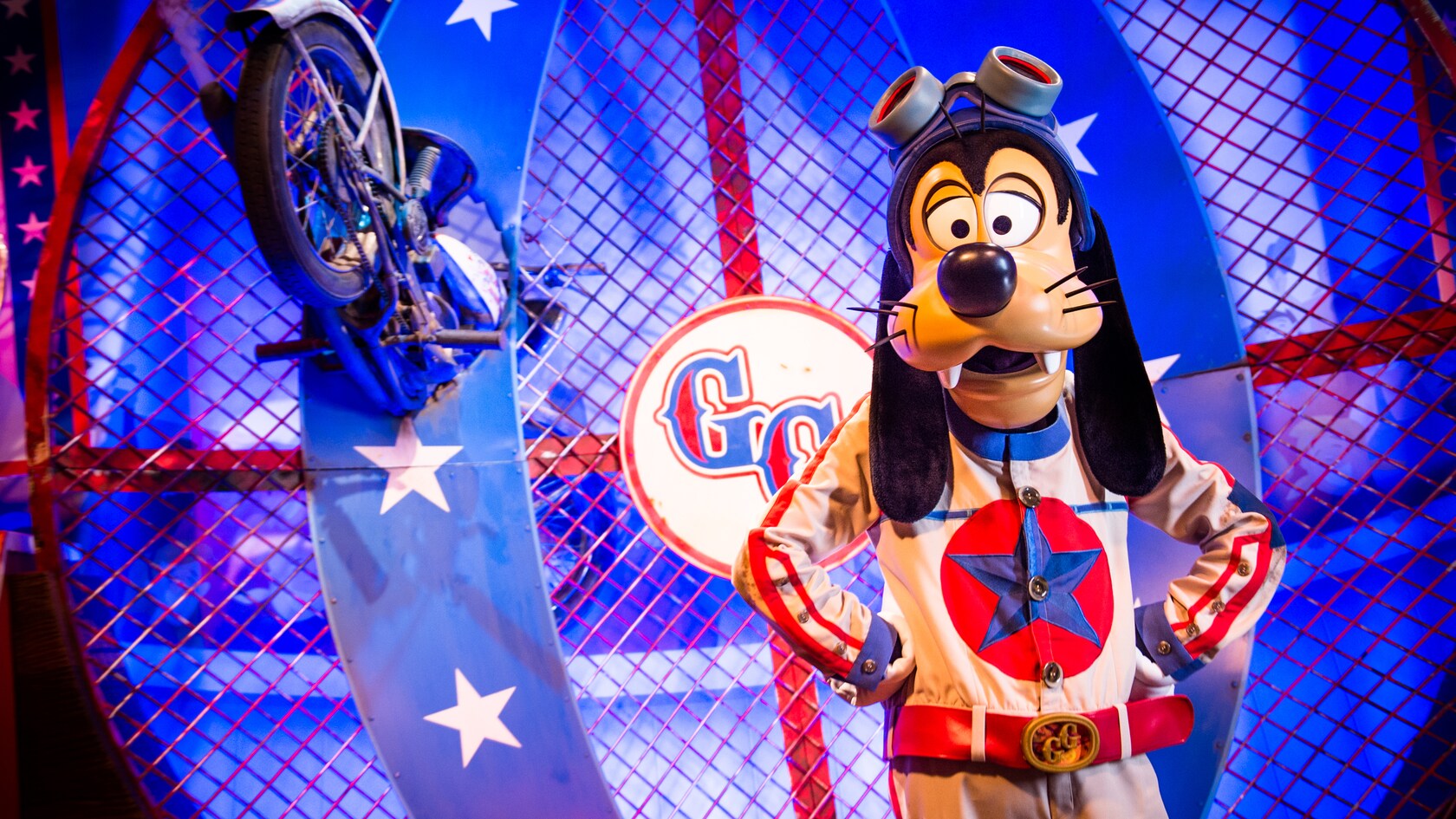 Goofy, as the Great Goofini, stands next to his crashed motorcycle in a caged motordrome
