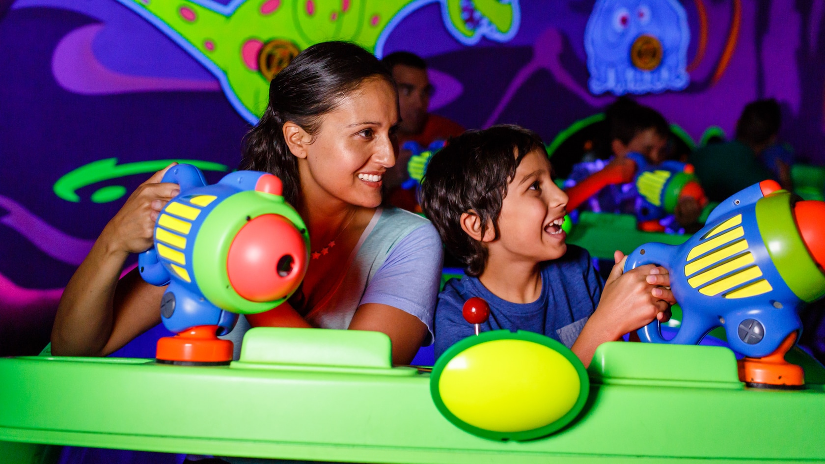 Une mère et son fils visent des canons de l’espace pendant le Buzz Lightyear’s Space Ranger Spin