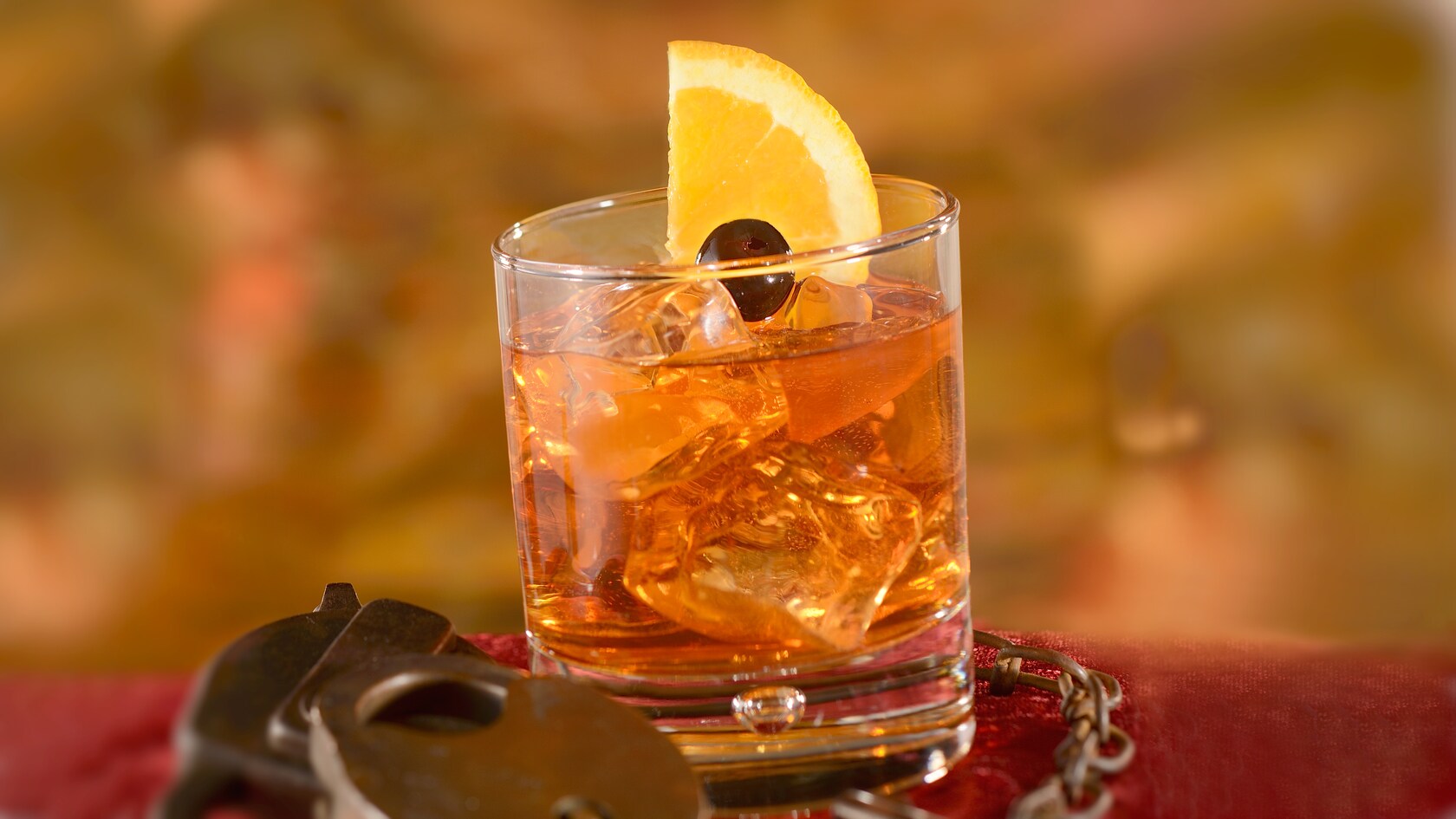 A specialty cocktail served in an Old Fashioned glass, garnished by a lemon slice and a black cherry