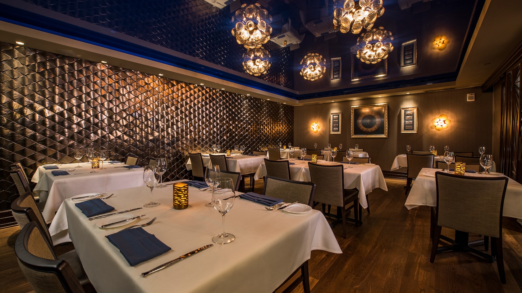 A tufted wall and chandeliers add a sophisticated backdrop to the impeccably set dining tables