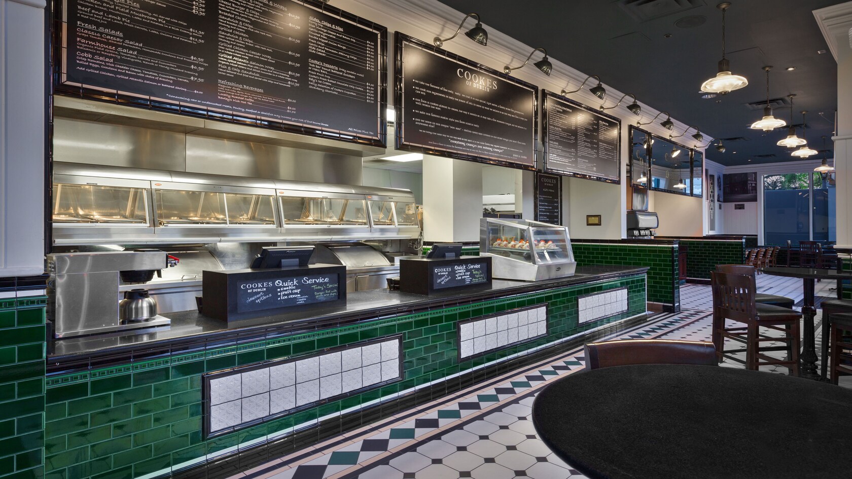 Ampla vista do balcão de atendimento de azulejos verde-e-branco em frente a mesas e cadeiras do bar