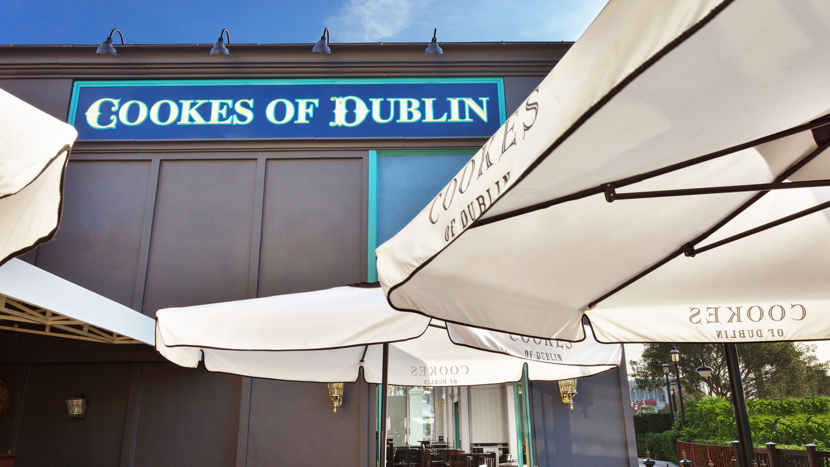 Placas externas e guarda-sóis brancos com o logotipo do Cookes of Dublin