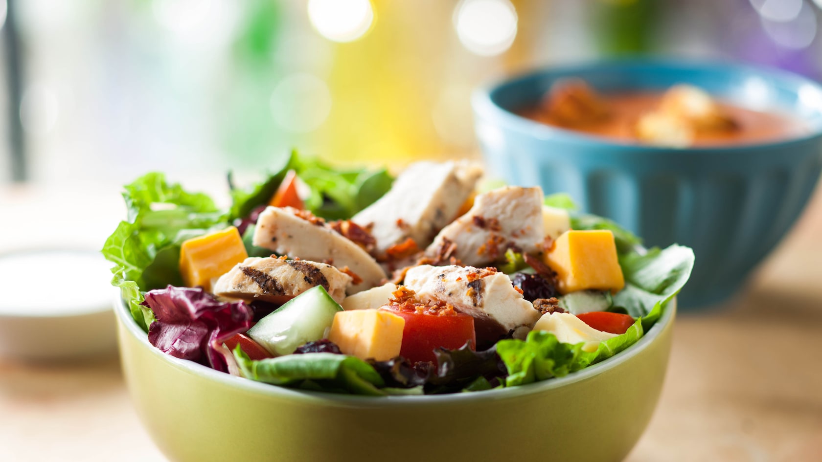 Uma tigela de salada Cobb do Earl com uma tigela de sopa de tomate em segundo plano