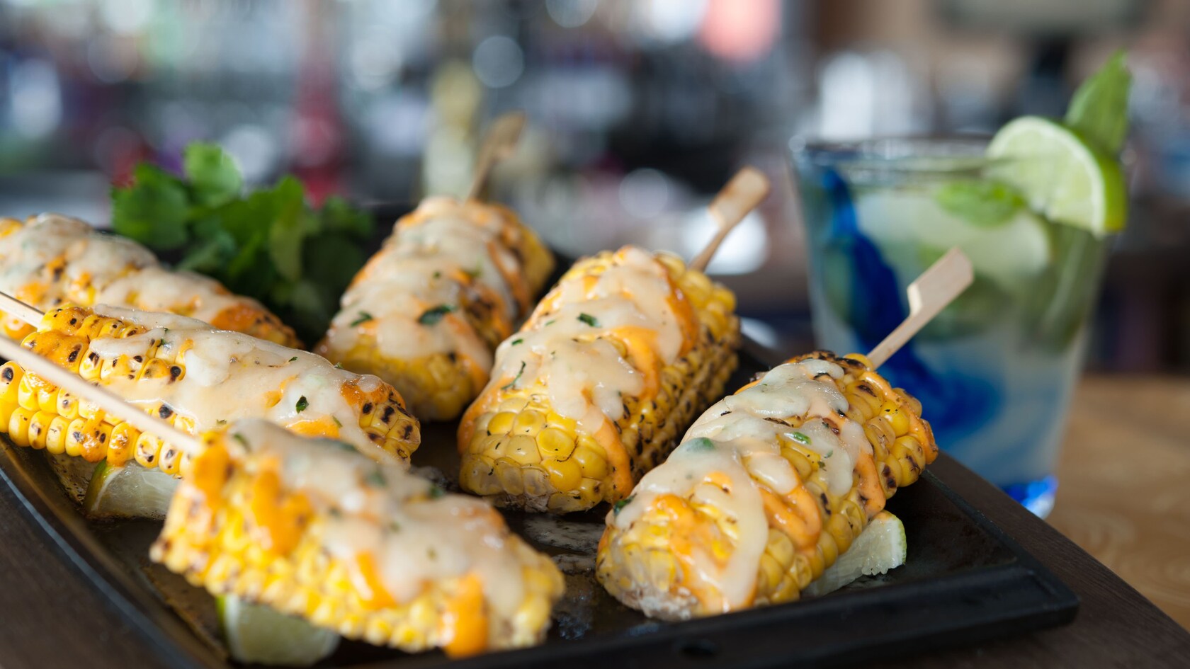 Six skewered Central American Crazy Corn on the cobs with spicy pepper sauce and melted cheese