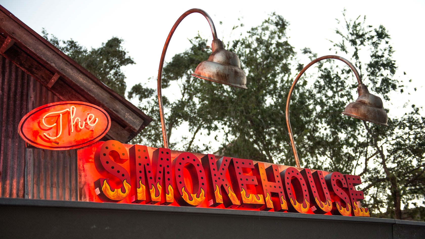 Un letrero con luces de neón de The Smokehouse, con letras que parecen herraduras en llamas