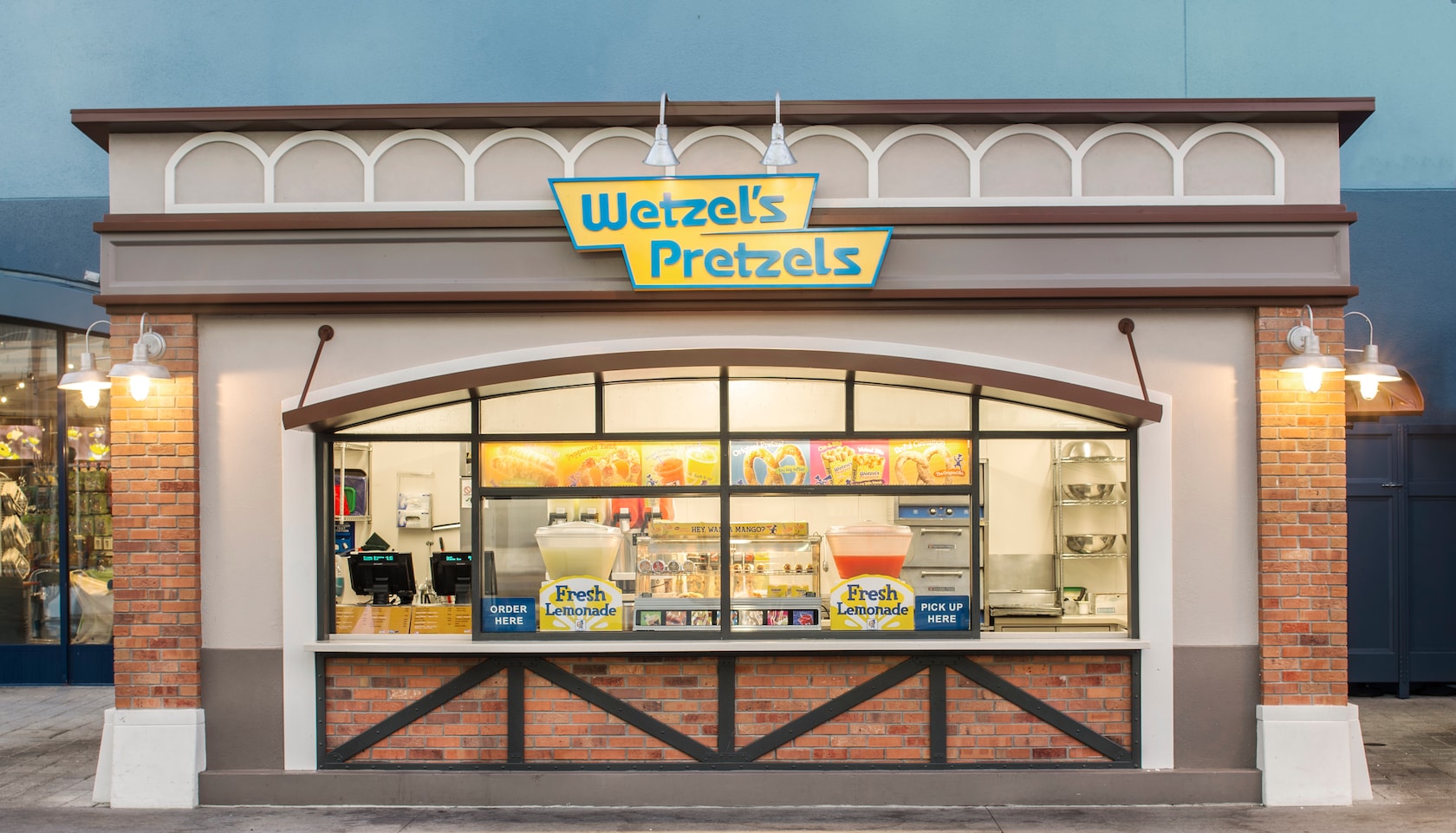 Un restaurante de servicio rápido al aire libre con 2 ventanas y un letrero que dice “Wetzel’s Pretzels”