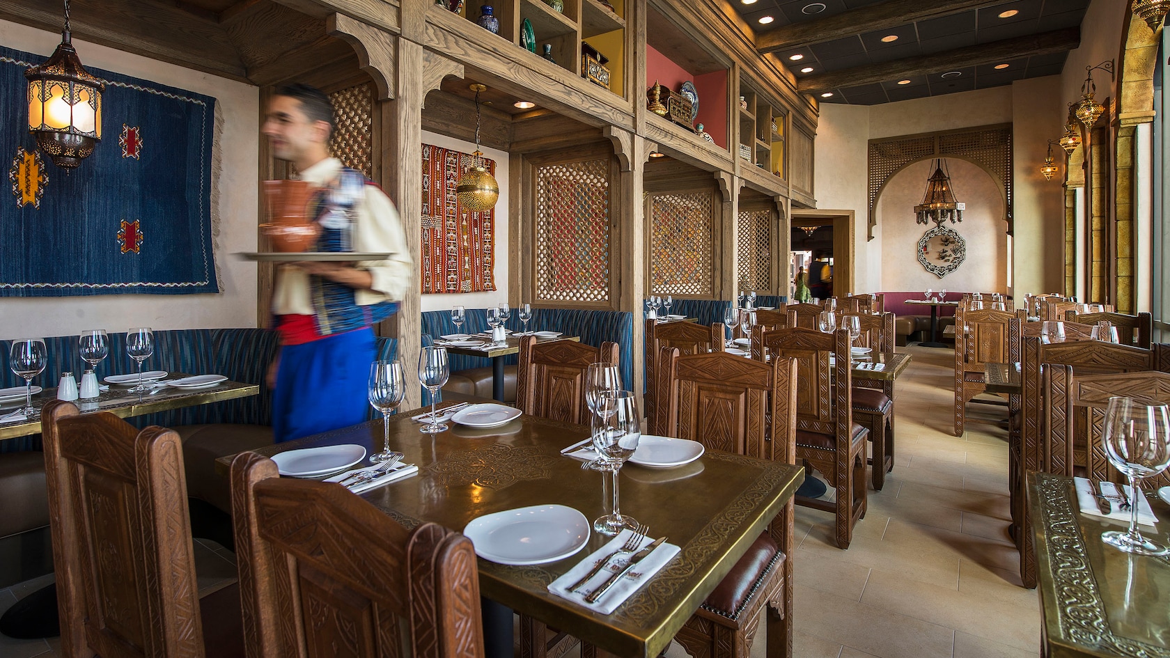 Un camarero lleva una bandeja en el área de comidas de un restaurante con temática marroquí