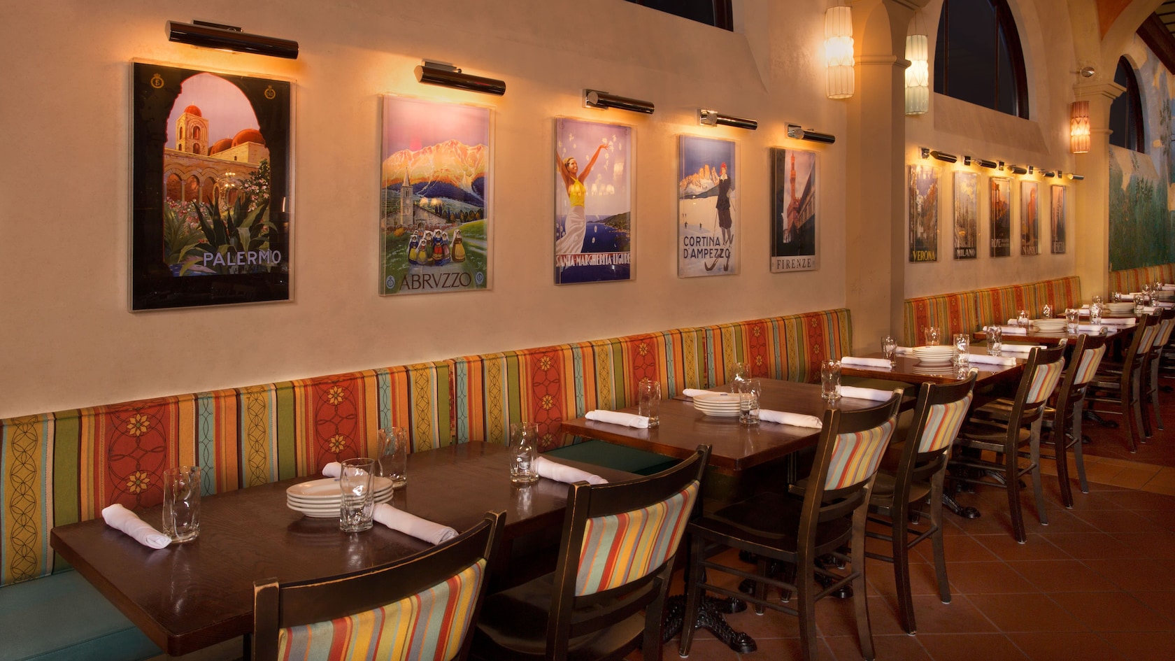 Lit travel posters on a dining-room wall above banquette seating