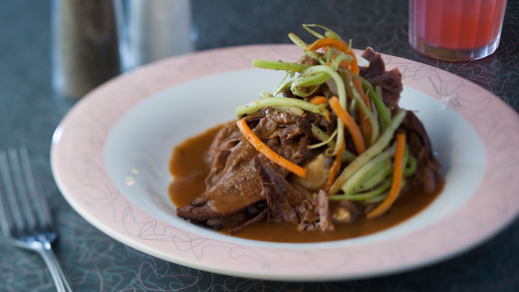 Une assiette de rôti avec de la sauce brune, des carottes, du céleri et des oignons