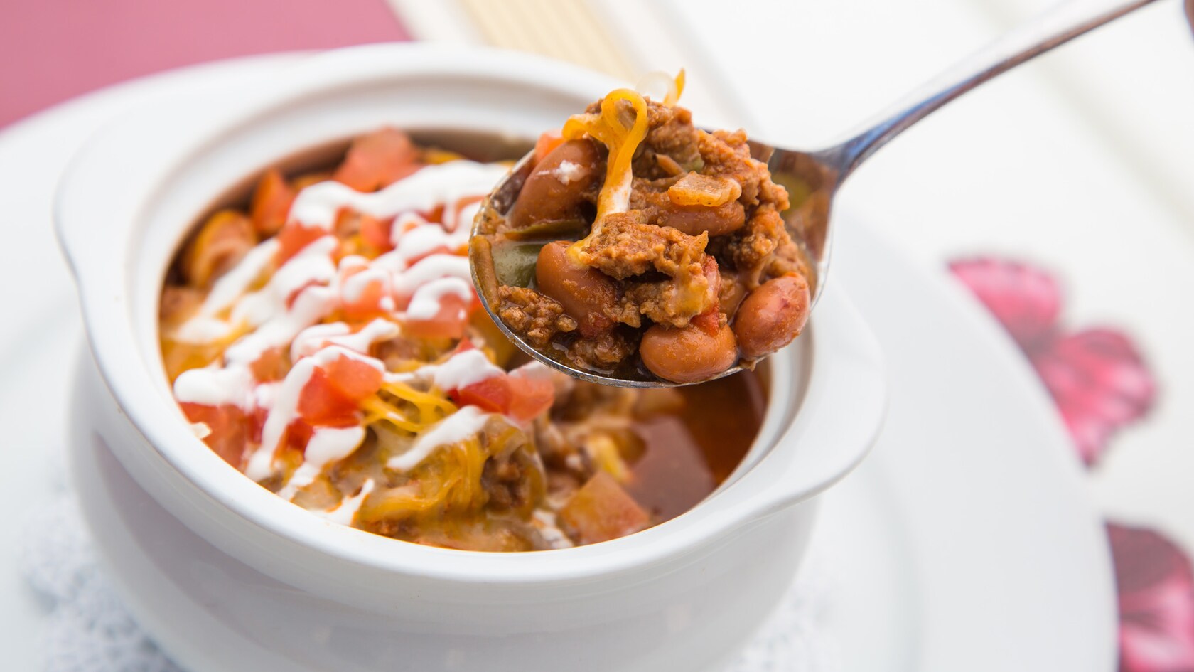 A heaping spoonful of chili above a bowl of chili