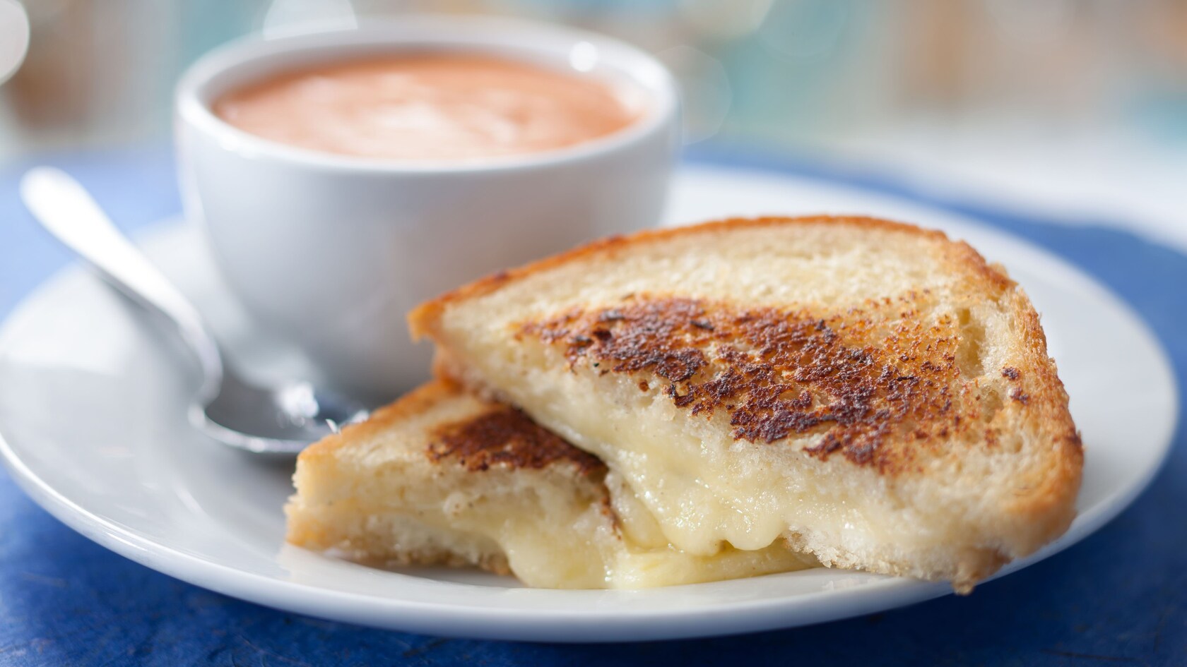 Grilled cheese sandwich with a cup of tomato soup on a plate