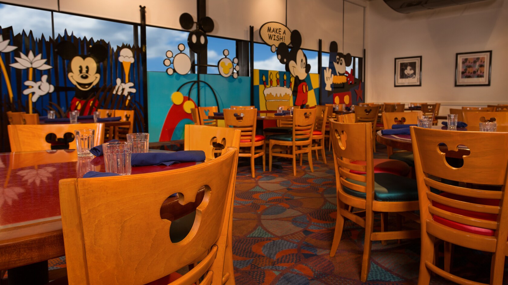 A section of the main dining area at Chef Mickey's, with a Mickey cartoon mural along the wall