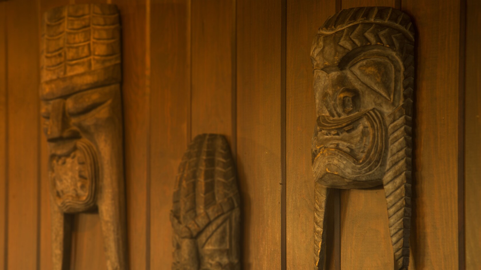 3 tiki sculptures hanging on a wall