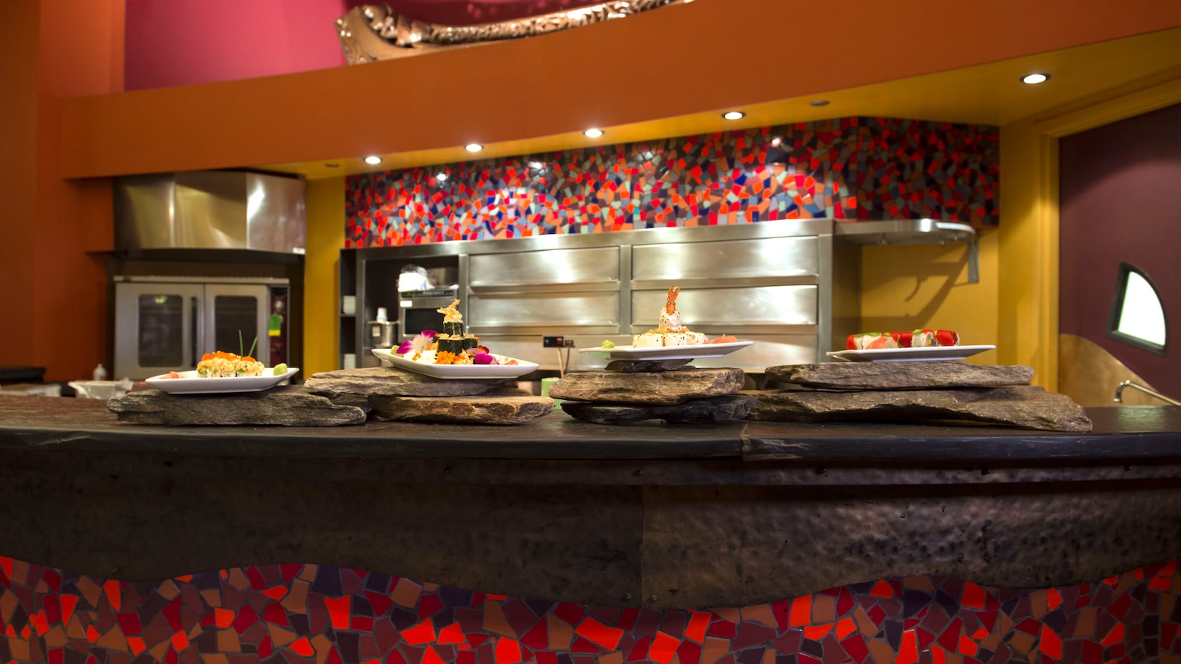 Platos de sushi habilidosamente preparados por el chef en el momento, sobre el mostrador de piedra y mosaicos de Kona Café