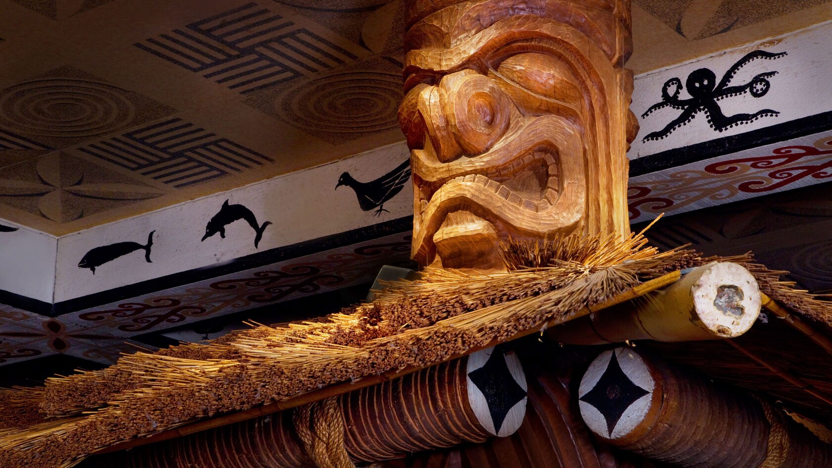 Tótems tiki tallados en madera que sirven de soporte al techo de paja sobre la barra