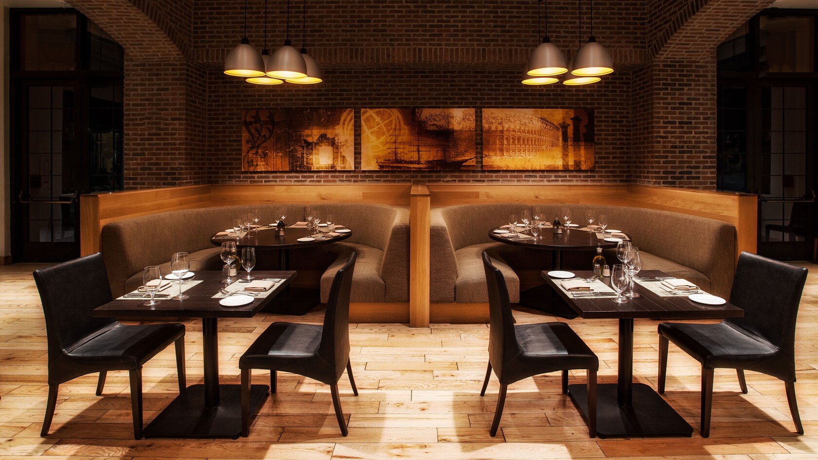 Two tables for 2 parallel to 2 large banquette booths against a brick wall