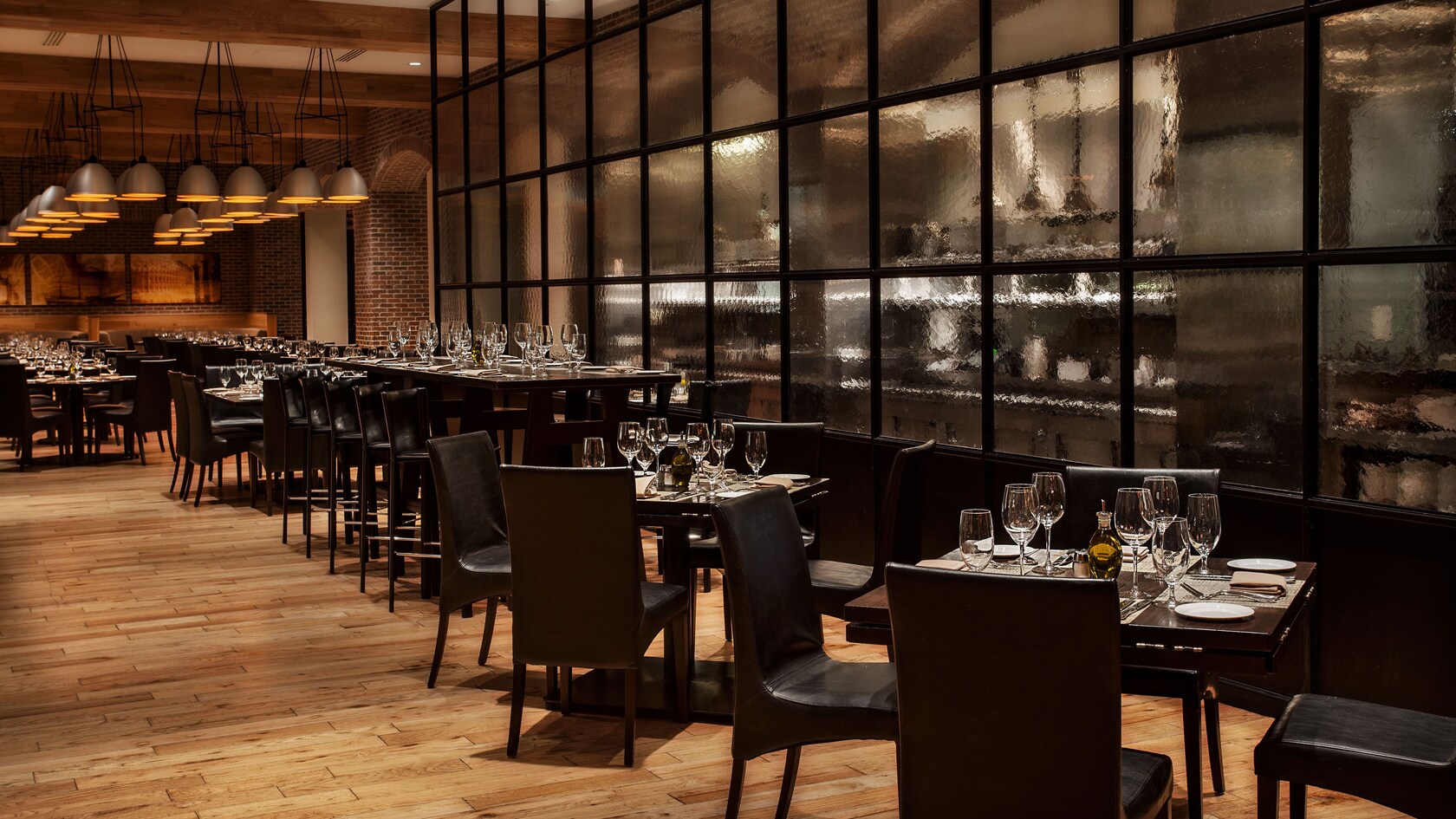 Tables alongside a tall textured-glass wall, with the open kitchen behind it