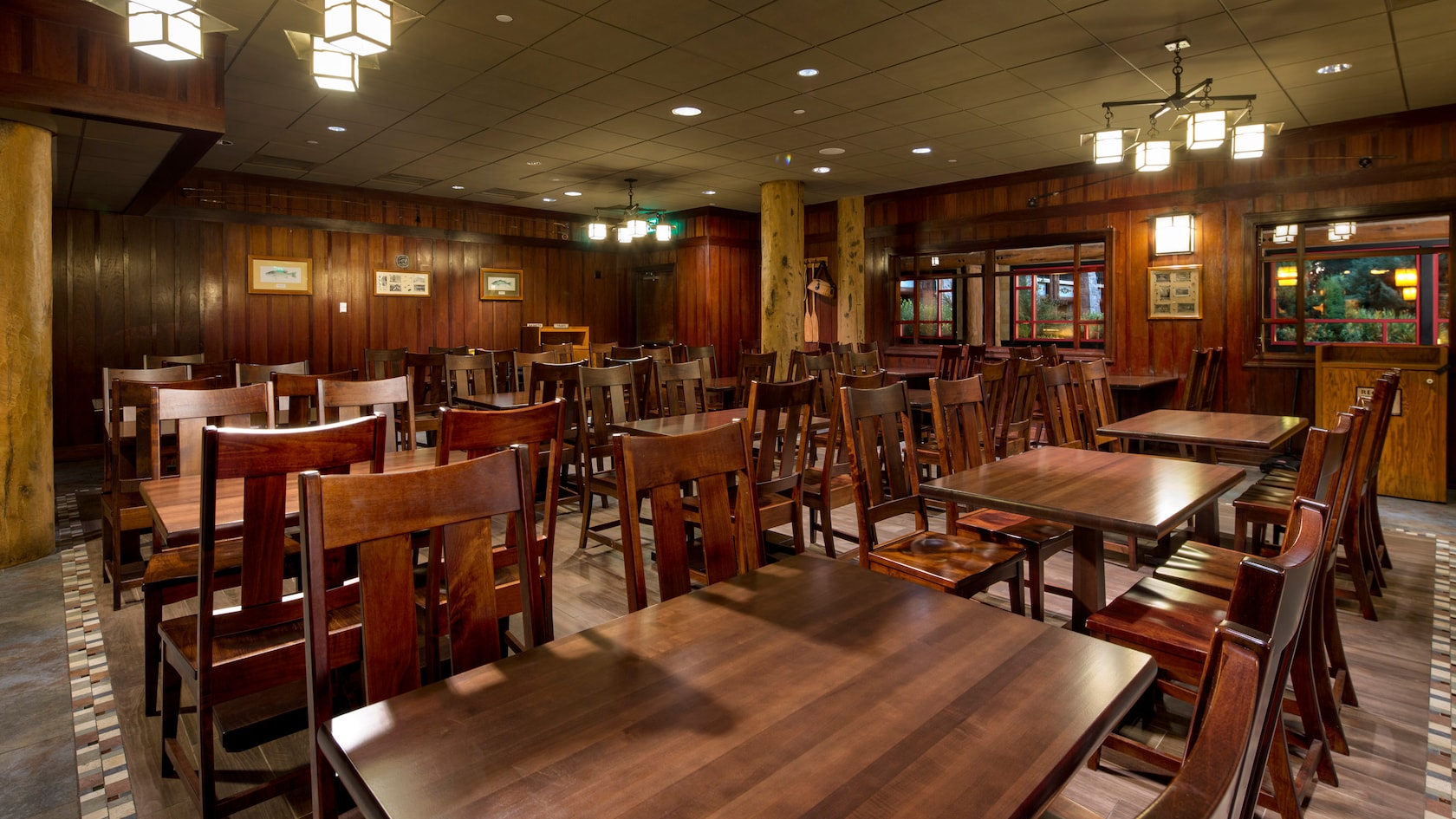 O salão de jantar de um restaurante com diversas mesas e cadeiras de madeira