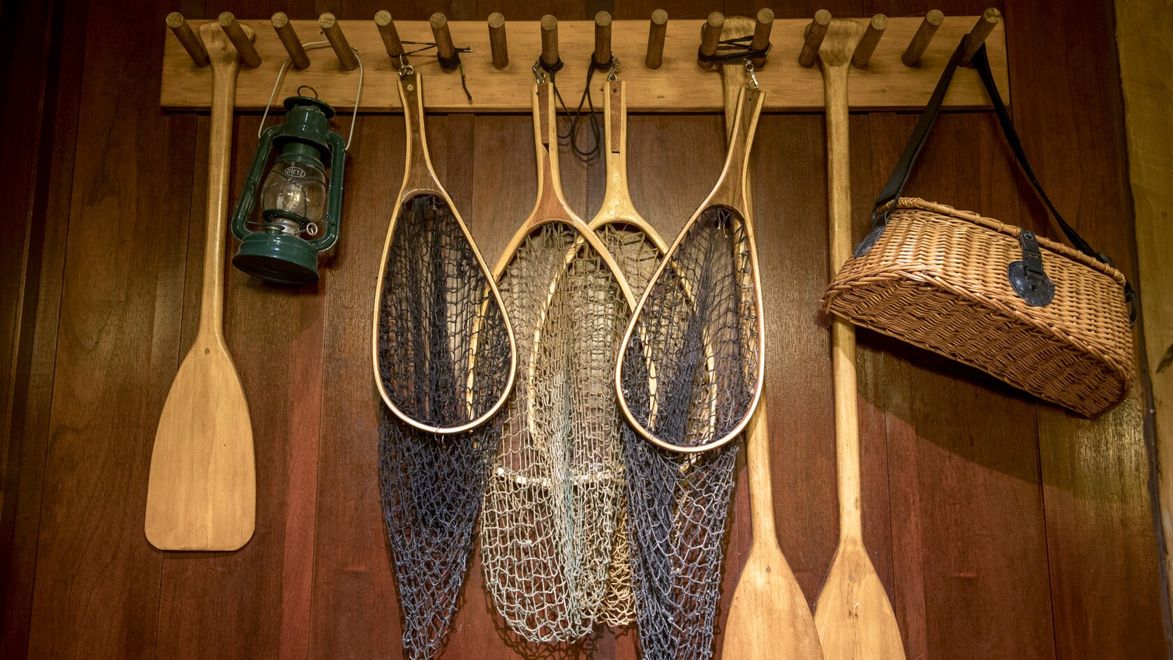 Vários itens de pesca pendurados em um rack, incluindo redes, remos e uma lanterna